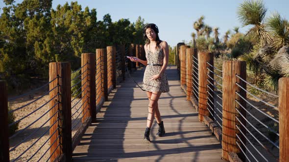 A beautiful young woman listening to music streaming from her smartphone on her headphones while wal alt