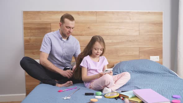 Careful Young Father Braiding Hair of Daughter