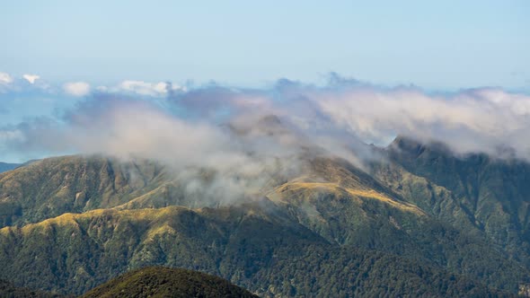 Foggy Clouds Moving over Mountains Ridge in Tararua Range Forest Park in New Zealand alt