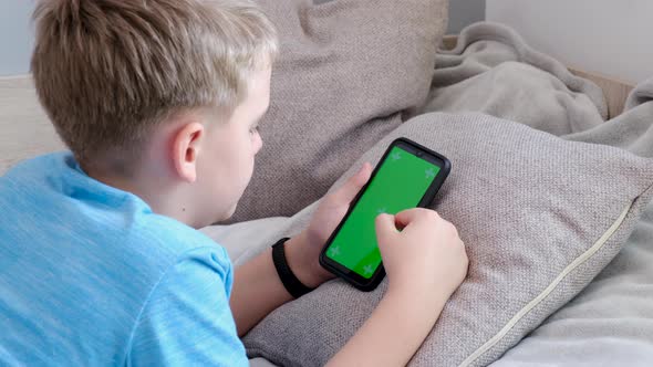 Boy Holding His Smartphone with Green Screen Scrolling Touching Screen alt