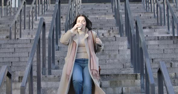 Adult Caucasian Woman Drinking Coffee As Running Down the Stairs and Looking at Her Watch. Young alt