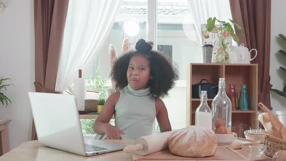 African American father girl and little girl using laptop together at kitchen table. Study at home