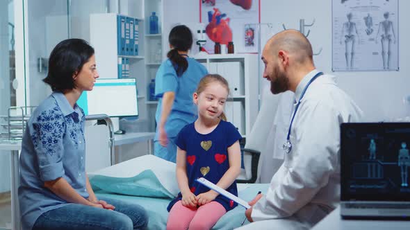 Doctor Talking with Little Girl Sitting on Bed alt