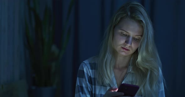 Young Beautiful Girl Sitting on the Bed with Her Phone