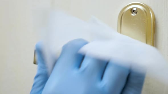 Close Up View of Hand in Medical Glove Using Antibacterial Wet Wipe for Disinfecting Room Door Knob