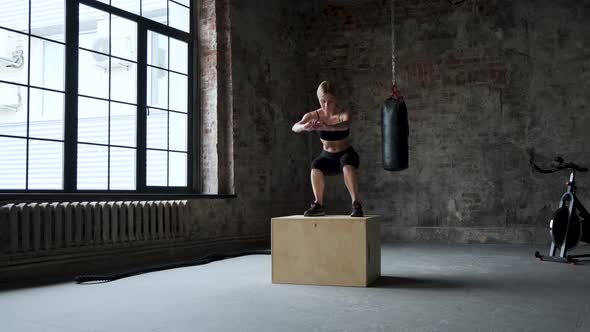 Fit Athletic Woman Does Box Jumps in the Deserted Factory Gym alt