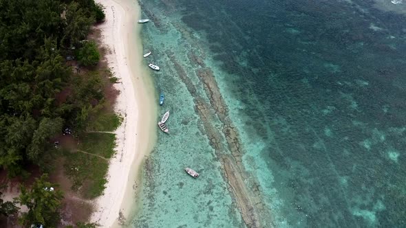 4K Drone Aerial Shot along beach coastline with anchored Boats Over Clear Blue Water alt