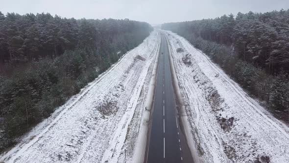 Winter highway, car and truck traffic. On the sides of the forest. alt