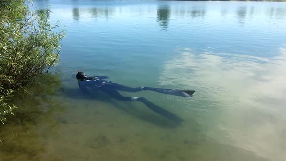 Underwater hunter swims in a lake in the summer