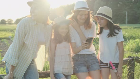 Happy Mother with Three Daughters Looking in Smartphone, Family in Nature alt