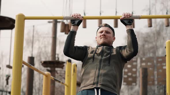 Young Bearded Man Is Doing Pull Ups Exercises on Horizontal Bar During Intense Workout Outdoors.