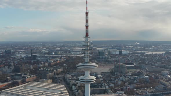 Aerial Dolly Out View of Tall White Heinrich Hertz TV Tower Rising Above Hamburg Cityscape alt