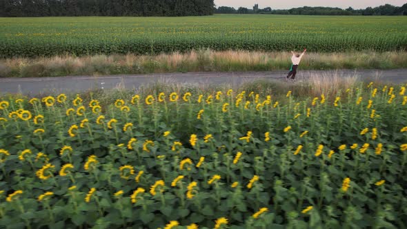 Aerial View of a Happy Child and His Mother Running Across the Field with Sunflower alt