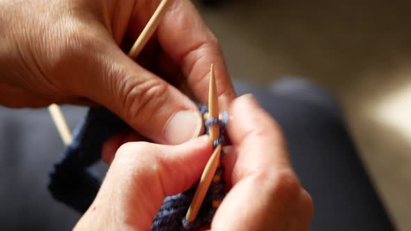 Woman is knitting socks with four needles, close up