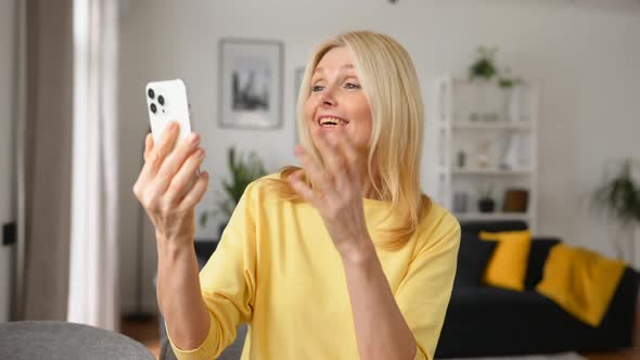 Happy Smiling Mature Woman Sitting in the Kitchen Talking Via Video Connection