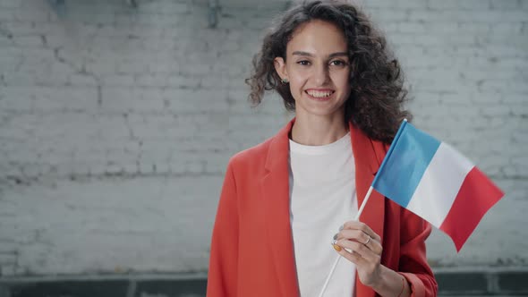 Portrait of Cute Young Woman Standing Outside with French Flag Smiling Looking at Camera alt