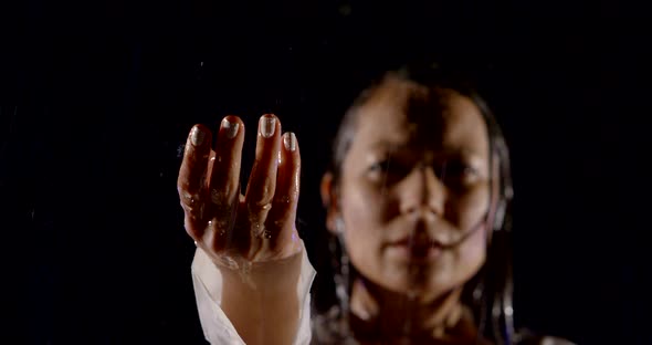 Sad and Sorrowful Woman Is Standing Under Rain in Nighttime, Catching Drops By Hand alt