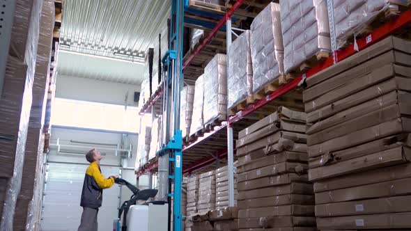 Warehouse Worker Driver in Uniform Delivery and Loading Cardboxes By Forklift Stacker Loader