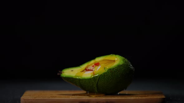 Olive Oil Spreading on Green Avocado in Slow Motion at Black Background alt