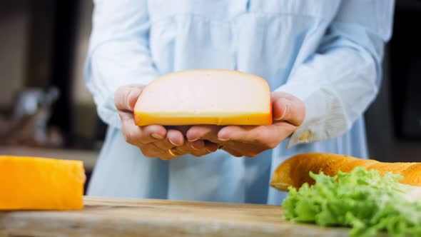 The Woman Holds in Her Hands a Piece of Cheese with Holes alt