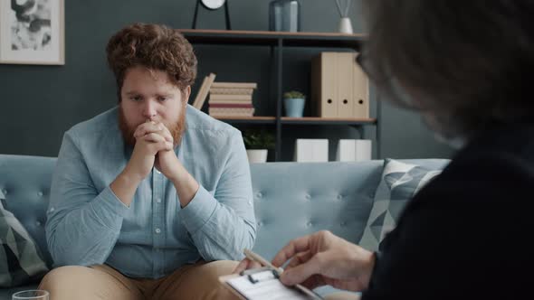 Worried and Sad Man Receiving Psychological Treatment in Therapist's Office alt
