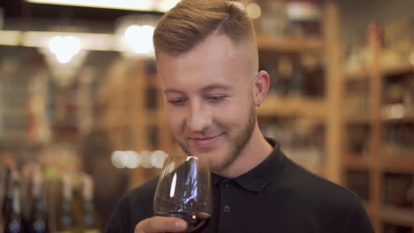 Male Visitor To a Liquor Store Takes the Offered Wine Glass and Sniffs the Aroma of the Wine alt