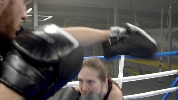 Young Woman Boxing with Coach in Gym