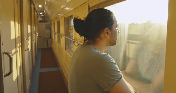 Young Attractive Tourist Looker Out of the Window of a Moving Train at Sunset