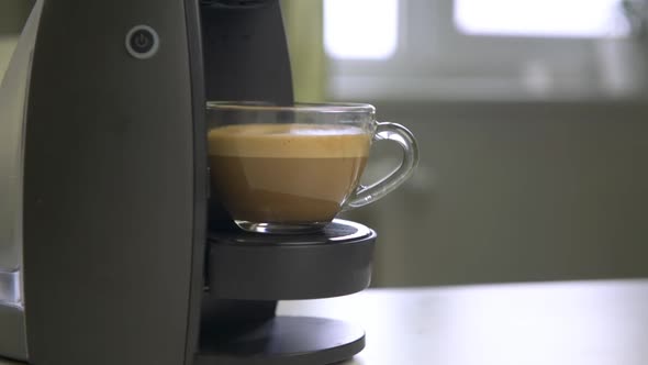 Female hand taking out prepared coffee with milk from coffee machine.