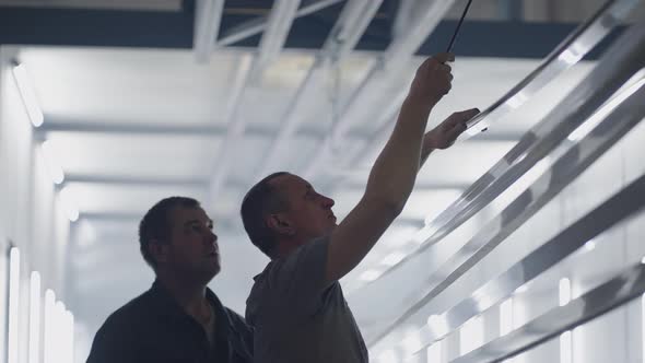 Two Working Male Painters Prepare Steel Metal Elements for Painting By Fixing Them on Suspensions alt
