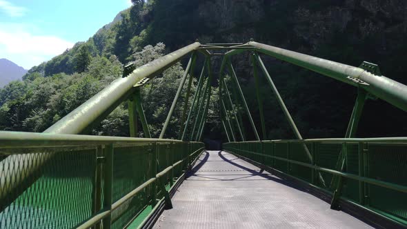 Movement Along a Green Metal Bridge Over the River in the Mountains alt