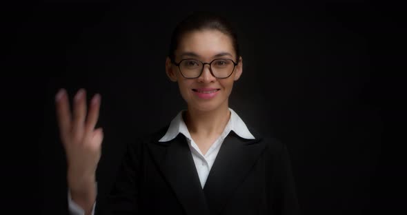 Asian Woman in Glasses Smiling and Shows Three Fingers with Her Right Hand