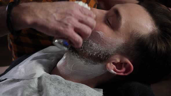 Barber Works with Shaving Brush White Foam on Client's Face