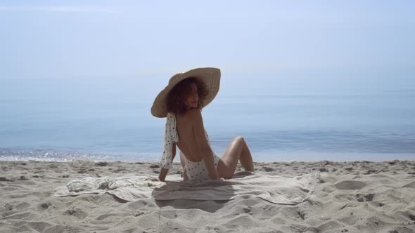 Stylish Woman Turning Back Sitting Sunny Seashore alt