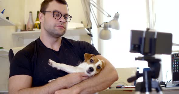Man Is Hugging His Dog and Filming Himself By Smartphone, Communicating To Camera alt
