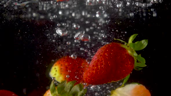 Closeup of fresh and healthy strawberries falling into clear water with big splash alt