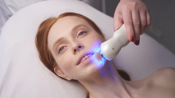 Portrait of a Woman on a Phonophoresis Machine. The Cosmetologist Moves the Manipulator  alt