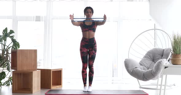 Fit black woman is training at home with elastic band.