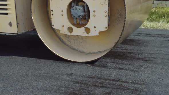 The roller levels and compacts the asphalt. Asphalt paver alt