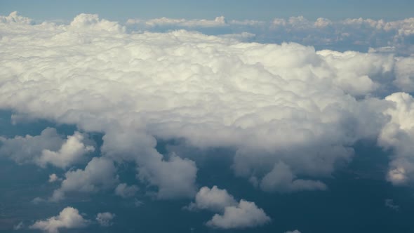 Aerial View From Airplane Window of White Puffy Clouds on Bright Sunny Day alt