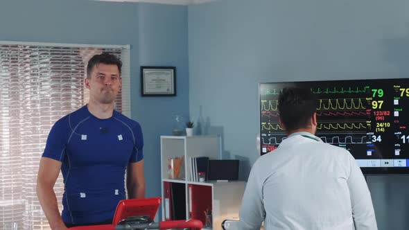 Handsome Athlete Being Tested and Monitored By Multiracial Doctor During Treadmill Test in Lab alt
