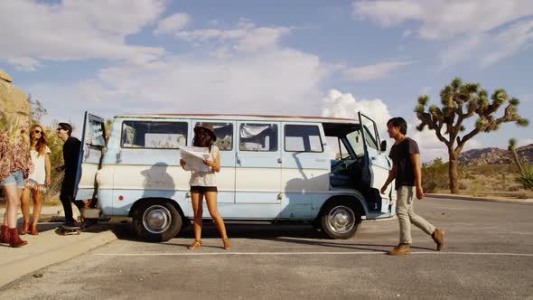 Group of young people on road trip look at map alt