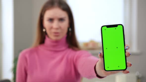 Closeup Green Screen Phone in Hand of Blurred Amazed Astonished Woman at Background alt