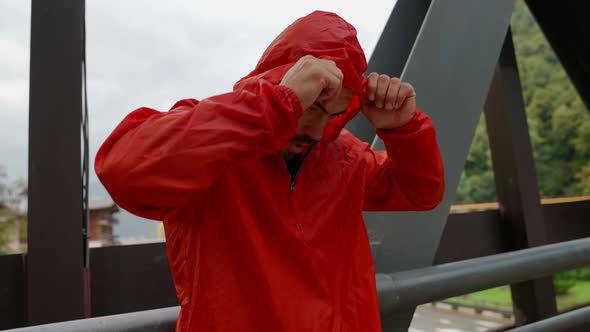 a Man in a Red Jacket Has Arms Crossed Over Chest and is Standing alt