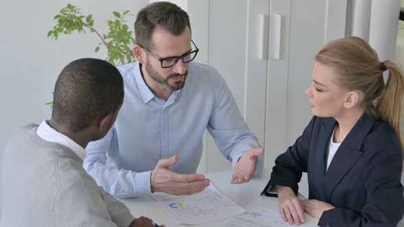 Businessman Explaining Papers to Male and Female Colleagues alt
