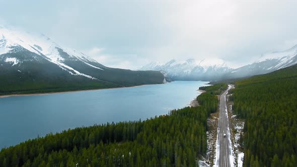 Aerial footage shows the road going along the forest and Spray Lakes Reservoir in Alberta, Canada alt