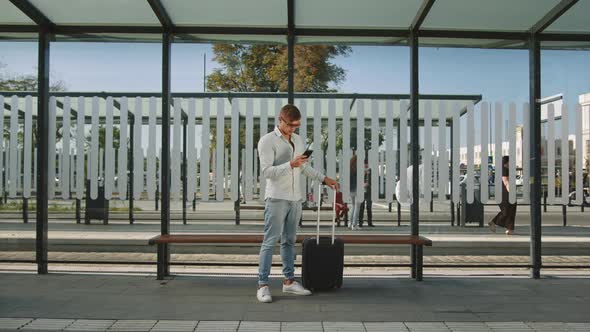 A Man is Standing at a Public Transport Stop alt