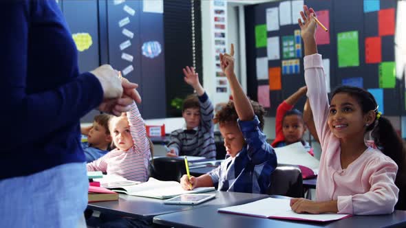 Schoolkid raising their hands in classroom alt