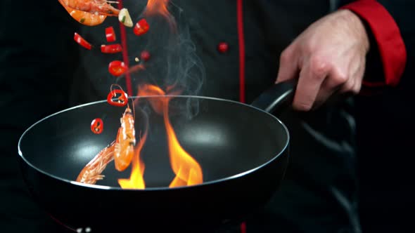 Super Slow Motion Shot of Chef Holding Frying Pan and Falling Shrimps Into Fire at 1000Fps. alt