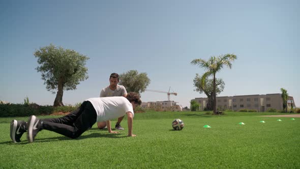 A Young Guy with a Personal Fitness Trainer Performs Pushups and Resistance Runs for Endurance and